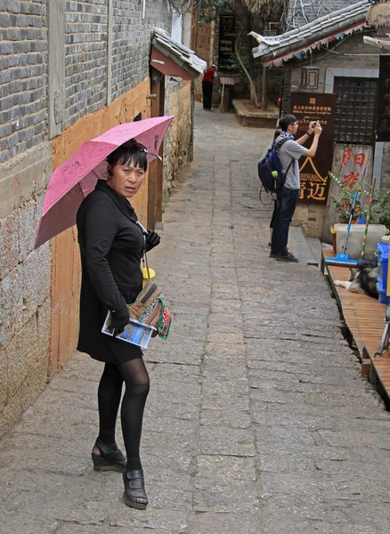 Kvinna med rosa paraply väntar på någon på gatan i Lijiang, China — Stockfoto