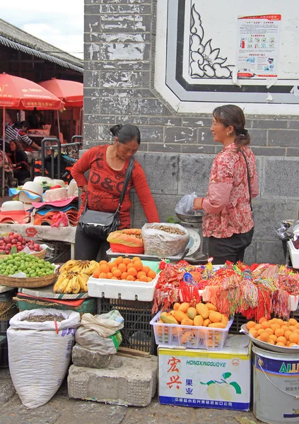 Mujeres están vendiendo frutas en el mercado en Lijiang — Foto de Stock