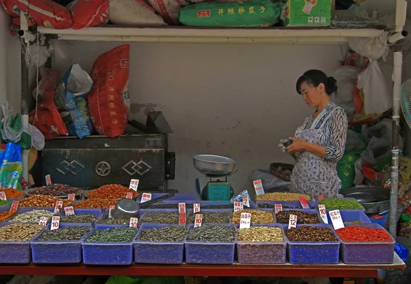 Mujer vende semillas, frutos secos y granos en el mercado en Lijiang — Foto de Stock