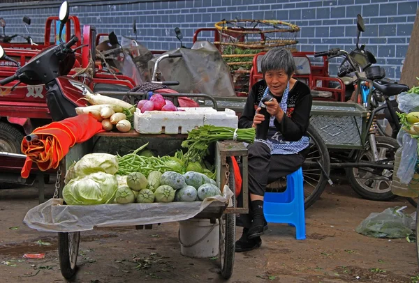 Mujer está vendiendo verduras en el mercado en Lijiang, China — Foto de Stock