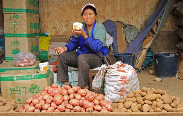 Vendedor de patatas está comiendo fideos en el mercado en Lijiang — Foto de Stock