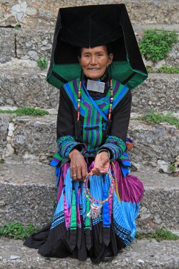 woman in bright colorful costume is sitting on the street