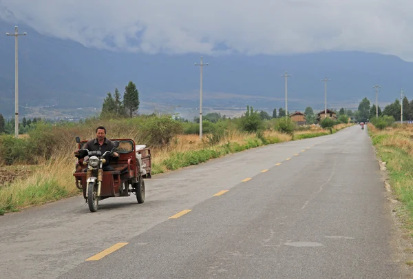 Man is driving motor tricycle on the road nearly Lijiang — Stock Photo, Image