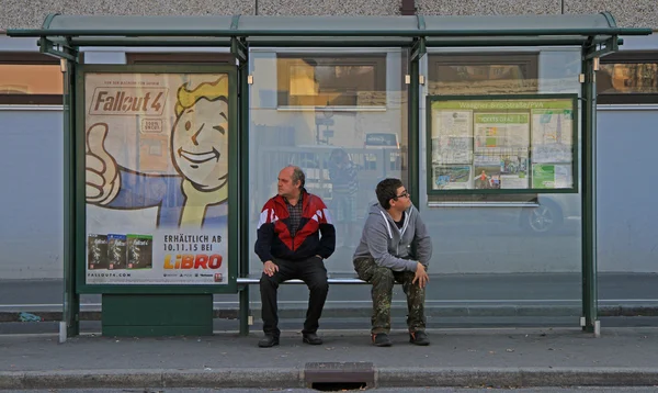 Két férfi várják a közlekedés a buszmegállóban — Stock Fotó