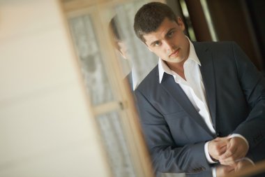 Yakışıklı ve güçlü bir adam resmi kıyafeti koyarak.