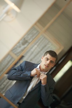 Yakışıklı ve güçlü bir adam resmi kıyafeti koyarak.