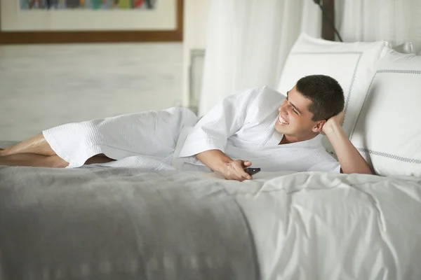 Gorgeous young man (gentleman) lying on a bed at the hotel.