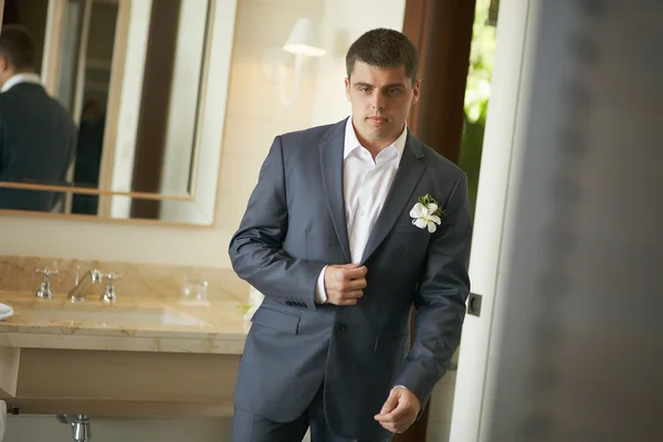 Yakışıklı ve güçlü bir adam resmi kıyafeti koyarak.