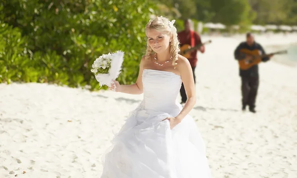 Gorgerous bride walking to wedding ceremony on the beach with bo