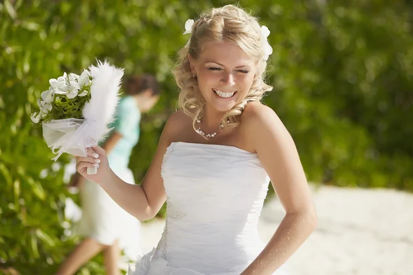 Gorgerous bride walking to wedding ceremony on the beach with bo