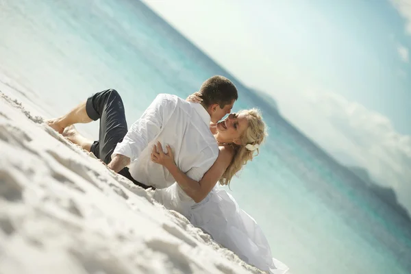 美丽的年轻夫妇亲吻日落躺在沙上，日落t — 图库照片