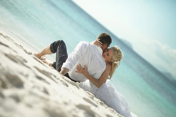 Красивая молодая пара целуется на закате лежа на песке, закат т т — стоковое фото