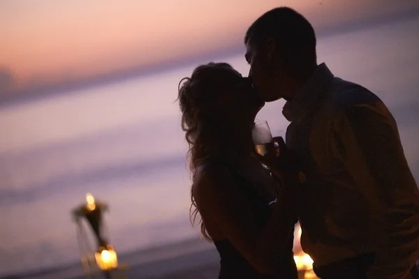 Hermosa pareja joven besándose en el crepúsculo, de pie cerca de la mesa . —  Fotos de Stock