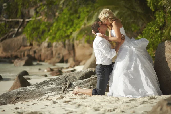 Beau jeune couple embrassant au coucher du soleil, debout pieds nus sur b — Photo