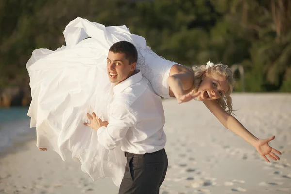 Hermosa pareja joven disfrutando de la puesta del sol, caminando descalzo en la playa — Foto de Stock