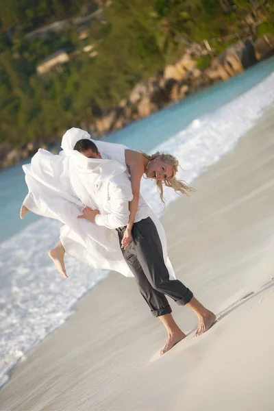 Hermosa pareja joven disfrutando de la puesta del sol, caminando descalzo en la playa — Foto de Stock