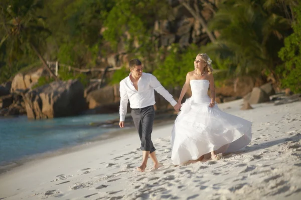 Hermosa pareja joven disfrutando de la puesta del sol, caminando descalzo en la playa — Foto de Stock