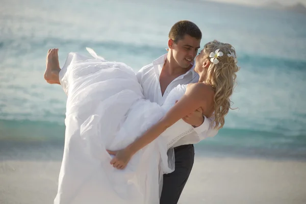 Hermosa pareja joven disfrutando de la puesta del sol, caminando descalzo en la playa —  Fotos de Stock