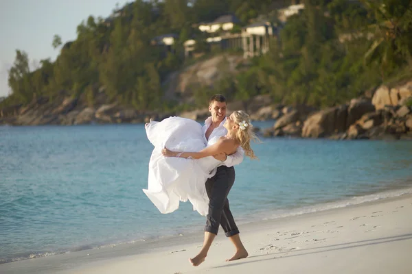 Hermosa pareja joven disfrutando de la puesta del sol, caminando descalzo en la playa — Foto de Stock