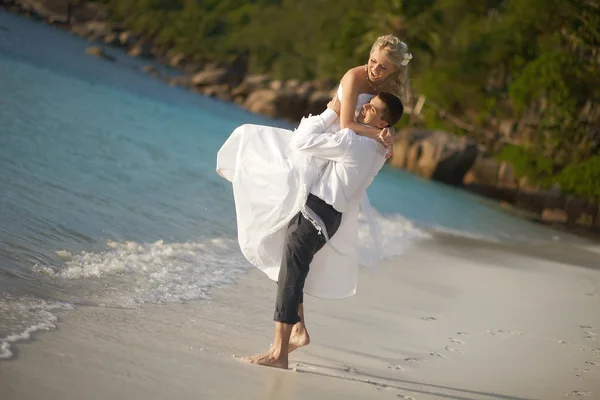 Hermosa pareja joven disfrutando de la puesta del sol, caminando descalzo en la playa —  Fotos de Stock