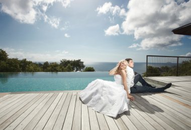 Beautiful young couple lying close to pool before wedding under 