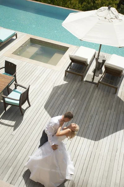 Lovely, gorgeous couple kissing close to pool area after wedding