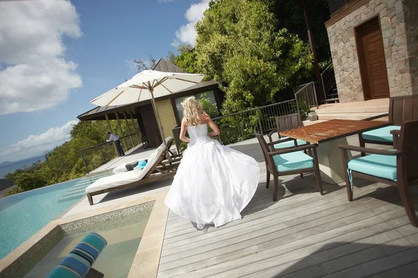 Lovely bride coming across pool area before wedding.
