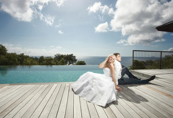 Belo jovem casal deitado perto da piscina antes do casamento sob — Fotografia de Stock
