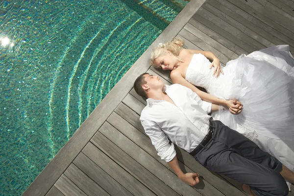Belo jovem casal deitado perto da piscina com ondas mentais . — Fotografia de Stock