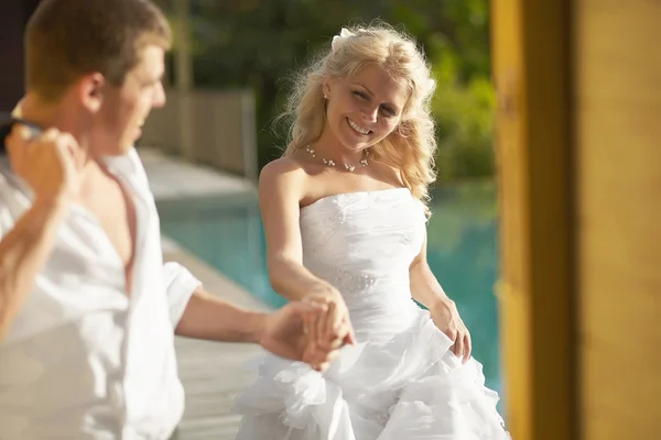 Szép menyasszony és a vőlegény jön át medence területén esküvő után. — Stock Fotó