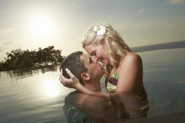 Young, sexy and attractive couple kissing in swimming pool in se — Zdjęcie stockowe