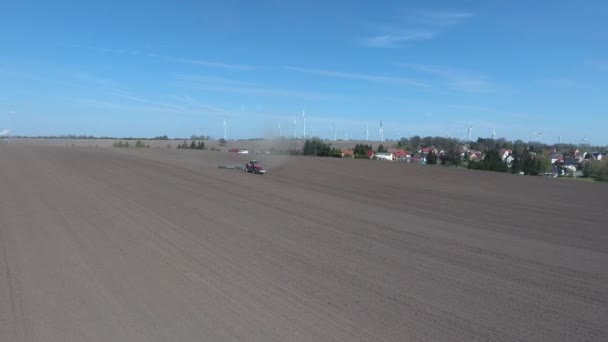 Luftaufnahme des Traktors, der im Frühling ein großes braunes Feld eggt — Stockvideo