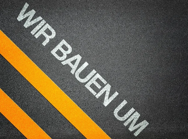 German - Wir bauen um - Text Writing Road Asphalt — Stock Photo, Image