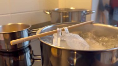 İçinde tahta bir sopa olan bir tencere kaynar su. Tencere ocağın üstünde.