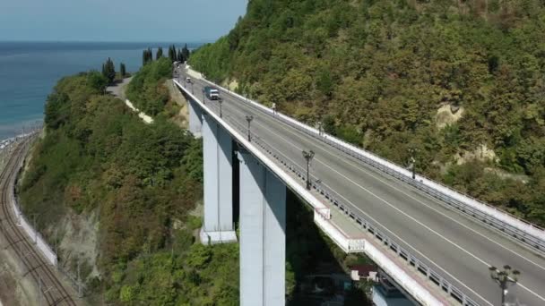 Vista de aves del puente de carretera situado en la costa del Mar Negro cerca de Sochi. Chemitokvadzhe. Los coches están conduciendo en la carretera. Árbol verde. — Vídeo de stock