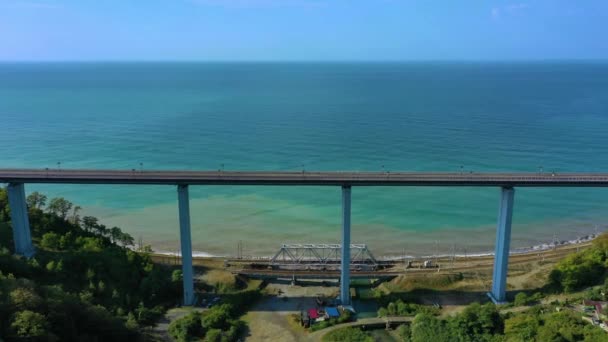 Vista lateral superior para os carros que dirigem na estrada nivelada no dia ensolarado. Panorama aéreo pitoresco do tráfego rodoviário e da cidade do sol. Sochi, Rússia. — Vídeo de Stock