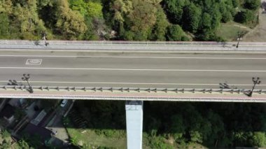 Yeşil çimlerle kaplı güzel tepelerin arasında kanyon üzerinde duran pitoresk kemer köprüsünün hava manzarası. Arabalar köprüden geçiyor. Gökyüzünün altında Rusya 'nın ünlü simgesi. 4K