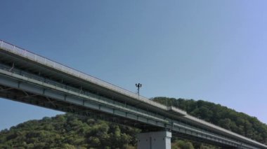 Yeşil çimlerle kaplı güzel tepelerin arasında kanyon üzerinde duran pitoresk kemer köprüsünün hava manzarası. Arabalar köprüyü hareket ettirir. Gökyüzünün altında Rusya 'nın ünlü simgesi. 