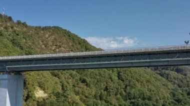 Resimli kemer köprüsünün hava manzarası kanyonun üzerinde güzel tepelerin arasında duruyor. Arabalar köprüden geçiyor. Gökyüzünün altında Rusya 'nın ünlü simgesi. 