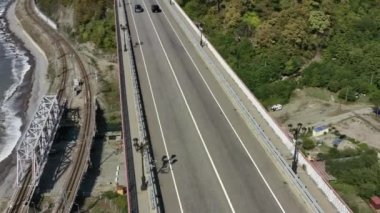Yeşil çimlerle kaplı güzel tepelerin arasında kanyon üzerinde duran pitoresk kemer köprüsünün hava manzarası. Arabalar köprüden geçiyor. Gökyüzünün altında Rusya 'nın ünlü simgesi. 