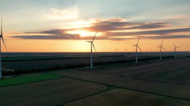 Rüzgâr parkı yavaş çekim drone dönüşü. Siluetler yel değirmenleri. Alternatif enerji. Rüzgar türbinlerinin hava görüntüsü günbatımında enerji üretimi 4K hava çekimi. İHA görüntüsü türbinler gün doğumunda bulutlarla 