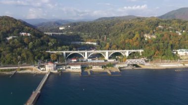 Havadan video çekimi. Köprünün üst manzarası. Deniz kenarında. Gün batımı. Soçi. Ufuktaki yüksek dağlar. Viyadük. Üst geçit. Deniz kıyısı boyunca demiryolu. Makesta