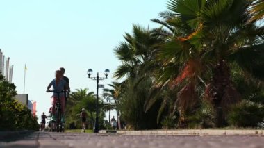 Sochi, Rusya - 2 Eylül 2020: kadın ve erkek sokakta birlikte araba kullanıyor. Şehirde yaşam tarzı ve sağlık. Kentsel arka planda motosiklet ve elektrikli scooter. Yavaş çekim video görüntüleri 