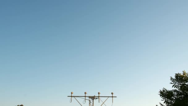 Посадка в аэропорту на закате. SLOW MIIION CLOSE UP: Коммерческий самолет летит прямо над камерой. Самолет пассажирских авиалиний, прибывающий и приземляющийся в крупном международном аэропорту. — стоковое видео
