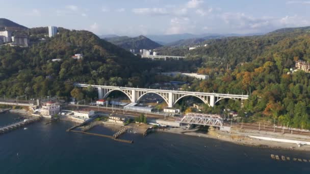 Flygfilminspelning. Ovanifrån av bron. Havssidan. Solnedgång. Sotji. Höga berg vid horisonten. Viadukt. Överfart. Järnväg längs kusten. Matcesta — Stockvideo