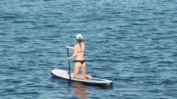 Ung flicka stå upp paddling på semester. Spårning skott av en ung kvinna SUP ombordstigning — Stockvideo