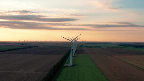 Große Windkraftanlagen mit Schaufeln im Feld Luftbild leuchtend orange Sonnenuntergang. Windpark Zeitlupe Drohne drehen. Silhouetten Windmühlen. Alternative Energien. Luftaufnahme von Windkraftanlagen — Stockvideo