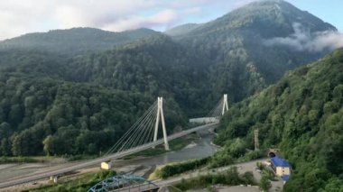 Uçuş yanlamasına modern kablolu yol köprüsü Sochi Rusya 'nın banliyö otoban araçları yüksek dağlar arasındaki vadi nehri arasında trafik yapıyor. Doğal manzara yeşil yamaçlar. Yaz güneşli. 