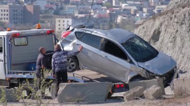 Bir vinç enkaz halindeki arabayı derin bir delikten çıkardı. Tahliye memuru. Kazanın kurbanı. Sigorta olayı.