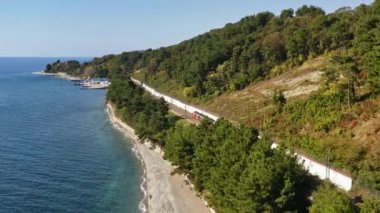 Güneşli bir günde bir yolcu treni sahil boyunca yol alır. Yut şunu. Rus Demiryolları. Sochi, Rusya. Elektrikli tren. Trip. Yolculuk. Nakliye aracı. Hava video çekimi.